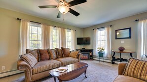 A living room with a sectional sofa, a coffee table, a fireplace, and a television. - Quiet Killingworth Rental w/ Deck & Grill! (Killingworth)