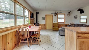 A spacious room with a wooden dining table and chairs, a large window, and a view of the outdoors. - Boat Dock & Fire Pit: Lakefront Monico Home! (Rhinelander)