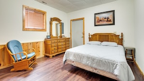 A bedroom with a wooden bed, a rocking chair, a dresser, and a mirror. - Boat Dock & Fire Pit: Lakefront Monico Home! (Rhinelander)