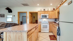 A kitchen with wooden cabinets, a white stove, and a microwave. - Boat Dock & Fire Pit: Lakefront Monico Home! (Rhinelander)