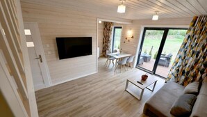 A modern living room with a flat-screen TV mounted on the wall, a sofa, a coffee table, and a dining area with a table and chairs. - House in Stepnica near Szczecin Lagoon (Stepnica)
