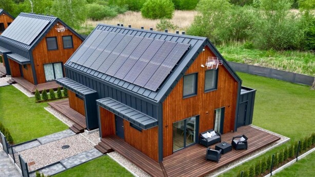 A modern wooden house with a sloped roof, solar panels, and a deck with outdoor seating. - House in Stepnica near Szczecin Lagoon (Stepnica)