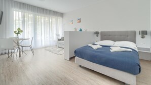 A modern bedroom with a large bed, a small table, and a chair.