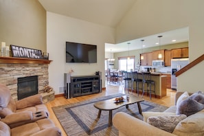 A spacious living room with a stone fireplace, a large flat-screen TV, and a cozy seating area.