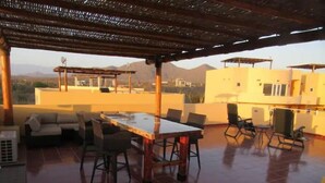 Une terrasse sur le toit, aménagée avec une table et des chaises pour les repas, un canapé et une pergola.