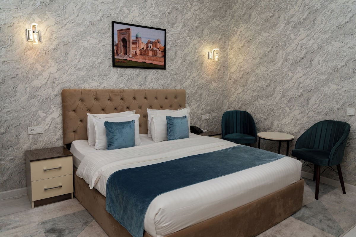 Une chambre à coucher avec un grand lit, deux tables de chevet, une chaise et une petite table ronde.