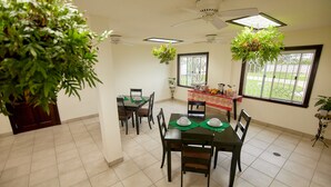 A dining area with a table set for four, chairs, ceiling fans, and potted plants. - King Studio - One
 (Georgetown)