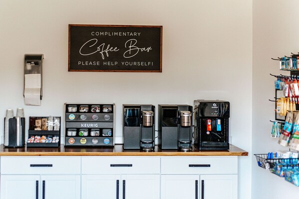 Una cafetería con varias máquinas Keurig, un molinillo de café y una variedad de cápsulas de café.