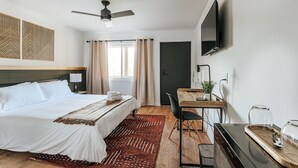 Une chambre d’hôtel équipée d’un lit, d’un bureau, d’une chaise, d’une télévision et d’une fenêtre avec des rideaux.