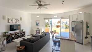 A modern living room with a sofa, TV, and ceiling fan.