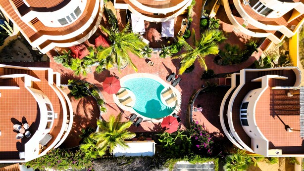 A resort with a central pool, multiple balconies, and lush landscaping.