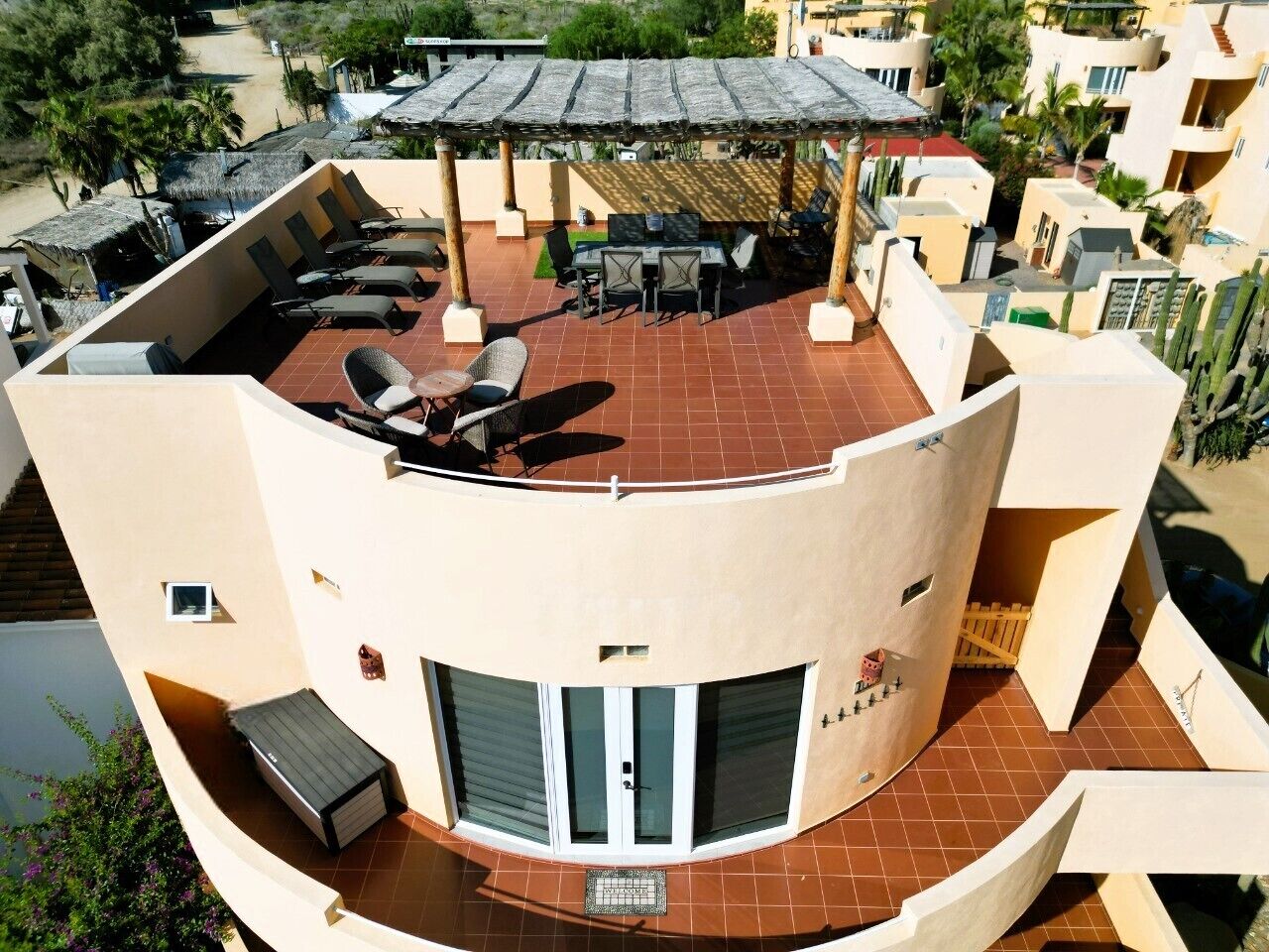 A curved building with a rooftop patio, outdoor seating, and a covered area with umbrellas.