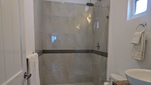 A modern bathroom with a glass-enclosed shower, a toilet, and a sink.