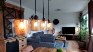 Ein modernes Wohnzimmer mit einem Holzesstisch, einem grauen Sofa und hängenden Pendelleuchten.