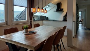 Eine moderne Küche mit Essbereich, ausgestattet mit einem Holztisch, braunen Stühlen und Pendelleuchten.