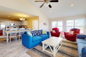 Relax in this open-plan living space with a kitchen area, featuring a sofa, coffee table, armchairs, dining table, and bicycle mounted on the wall.