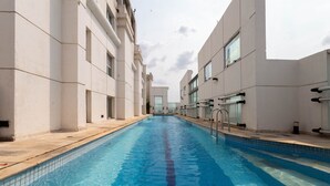 Ein Swimmingpool mit klarem, blauem Wasser, umgeben von modernen Gebäuden mit großen Fenstern und einer gefliesten Terrasse.