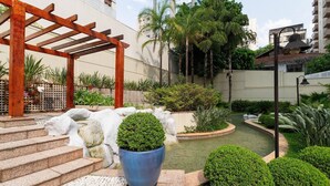 Ein Innenhof mit einer Pergola, Treppen zu einem Pool und verschiedenen Pflanzen.
