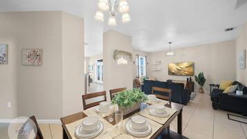 Un coin repas avec une table dressée pour quatre personnes, un canapé et un lustre.