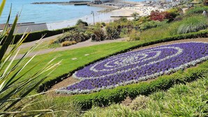Un paysage côtier avec un jardin fleuri, une plage et une jetée.
