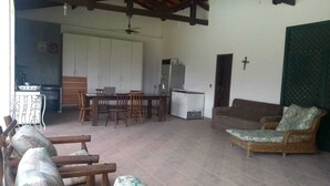 A spacious living area with a dining table, chairs, a sofa, and a kitchen area with a refrigerator.