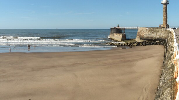 Una playa con un faro y un muelle.