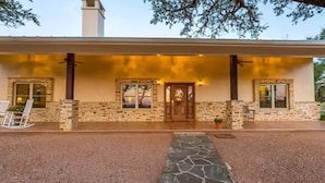 A two-story building with a stone facade, a front porch, and a gravel driveway. - Stunning Fredericksburg Ranch House with Pool and Hot Tub! (Fredericksburg)