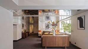 A modern lobby with a reception desk, seating area, and large windows allowing natural light. - Hotel Stoller (Zürich)