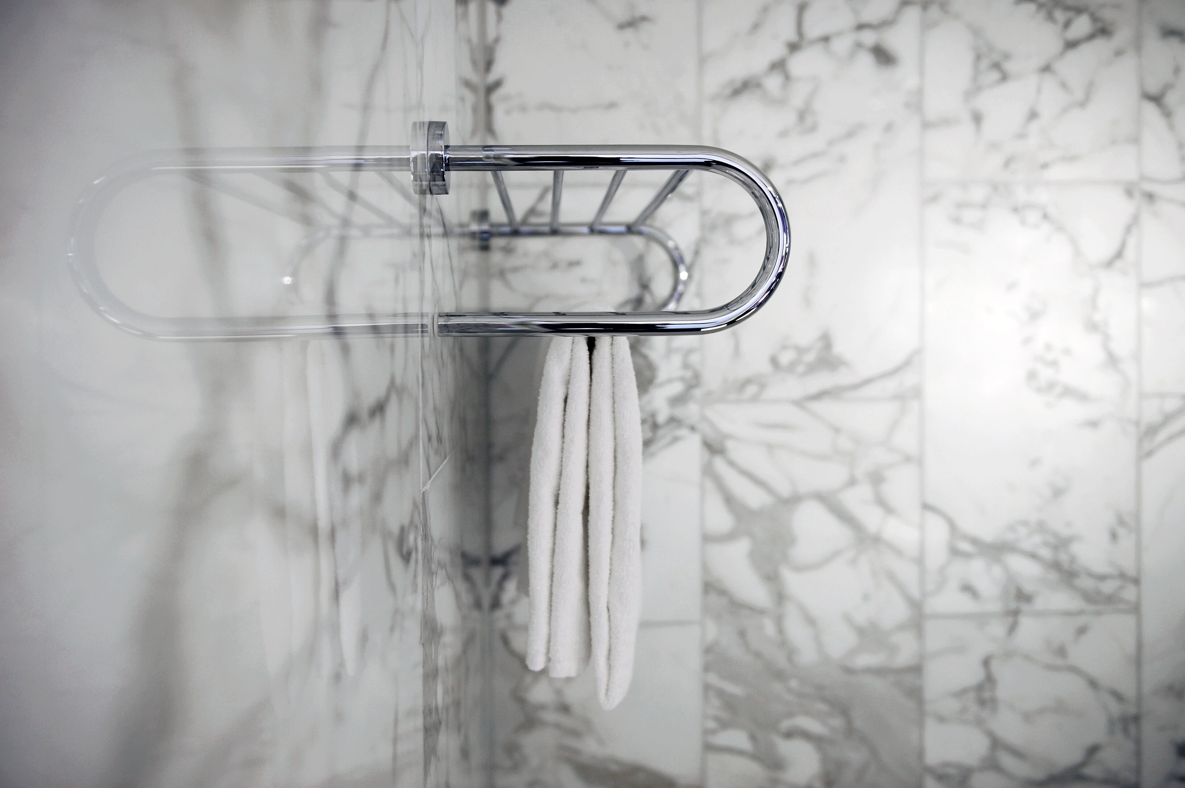 A bathroom with a towel rack holding white towels.