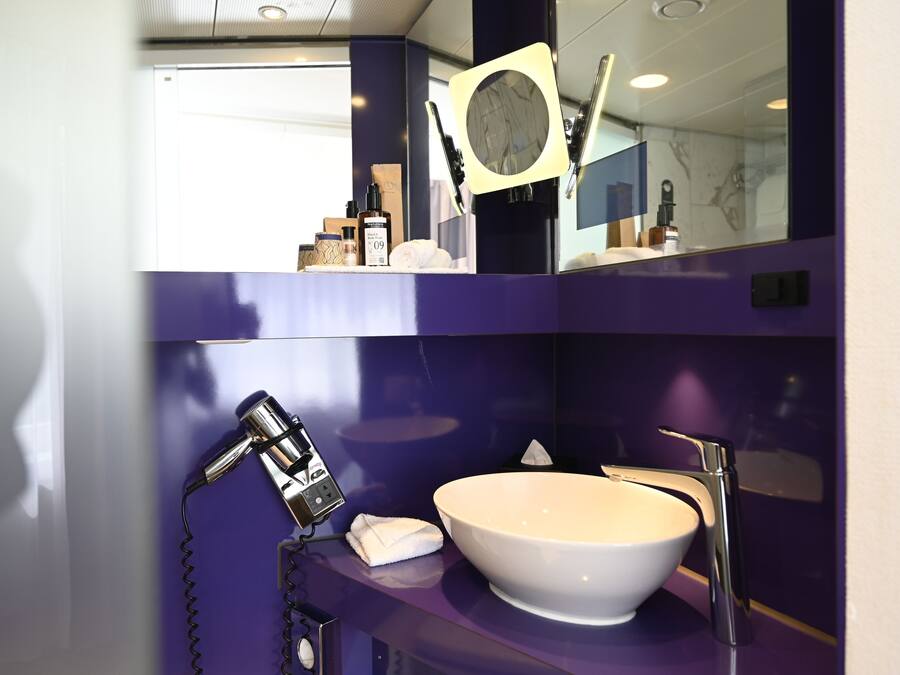 A bathroom with a white sink, a handheld showerhead, and a mirror with a round frame.