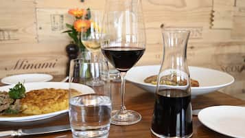 A dining table with plates of food, glasses of water and wine, and a vase with flowers.