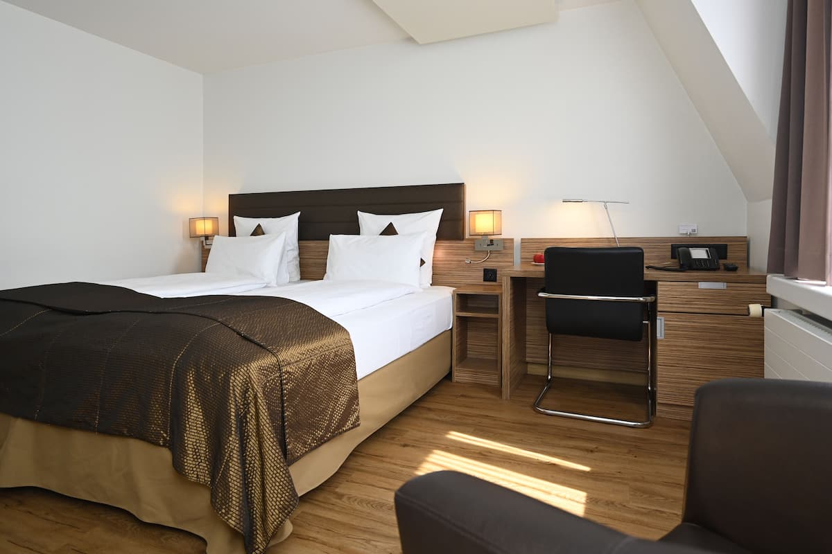 A modern hotel room with a large bed, bedside tables, a desk, and a chair.