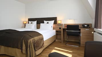 Una habitación de hotel moderna con una cama grande, mesitas de noche, un escritorio y una silla.