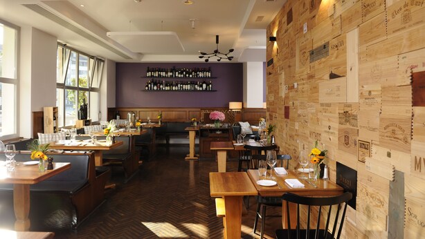 A restaurant with wooden walls, a herringbone floor, and a wine rack on the wall. - Hotel Stoller (Zürich)