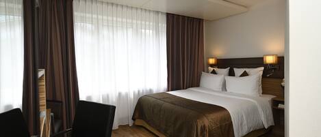 Une chambre d’hôtel avec un grand lit, un bureau et une chaise.