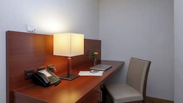 Un mostrador de recepción de hotel con un teléfono, una lámpara, un ordenador portátil y una silla.