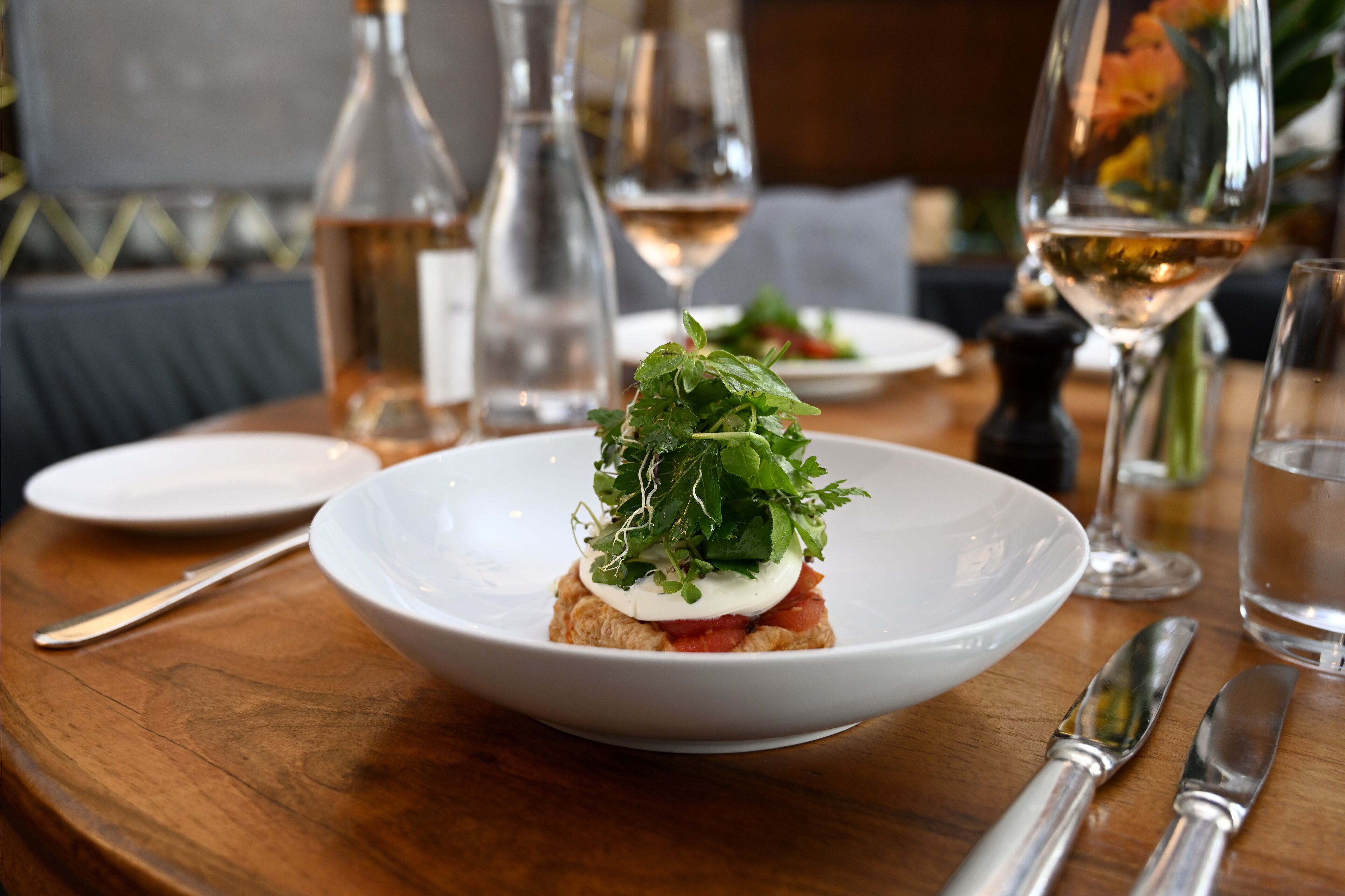 A dining table with a white plate containing a food item, a knife, and a fork.