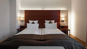 A hotel room with a large bed, two bedside tables, and wall-mounted lamps. - Hotel Stoller (Zürich)
