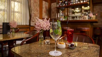 Angolo bar con un bancone in granito, un bicchiere di cocktail guarnito con menta e una bevanda rossa sullo sfondo.