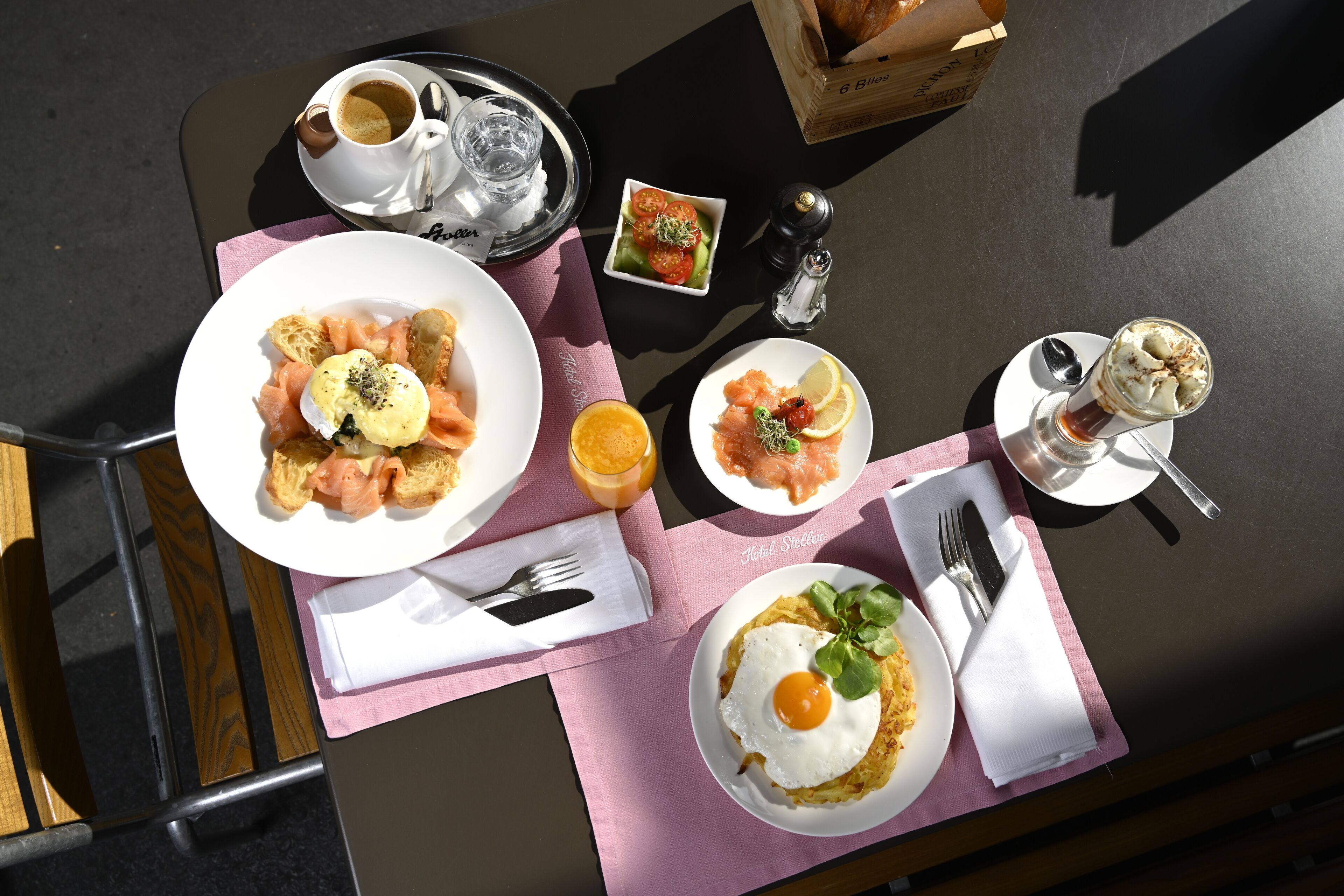 A table with breakfast items including eggs, smoked salmon, and toast, along with a coffee and a glass of orange juice.