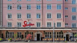 A pink hotel with multiple windows, a restaurant, and outdoor seating. - Hotel Stoller (Zürich)