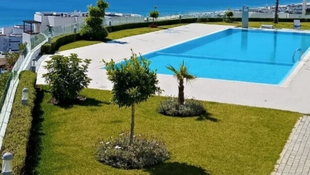 Une piscine offrant une vue dégagée sur la mer et les montagnes en arrière-plan.