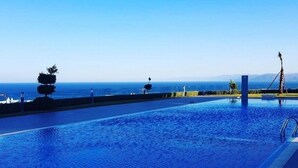 Une piscine offrant une vue dégagée sur l’océan et les montagnes en arrière-plan.