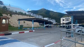 Un espace de stationnement doté d’une structure abritée, d’un petit kiosque et ayant une chaîne de montagnes en arrière-plan.