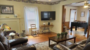 A living room with leather sofas, a coffee table, a TV, a fireplace, and a foosball table.