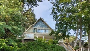 A house with a stone retaining wall, a wooden deck, and a dock extending into a body of water. - Friendship Lodge Total package lake house, tasteful décor, magnificent lakeview (Maryland)