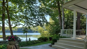 A covered outdoor area with a view of a lake, surrounded by trees and a well-maintained lawn. - Friendship Lodge Total package lake house, tasteful décor, magnificent lakeview (Maryland)
