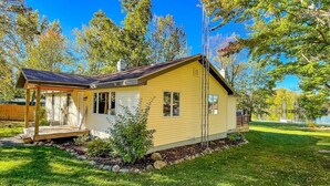 Une maison de plain-pied avec un porche, un petit jardin et une vue sur un lac.
