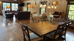 A wooden interior with a dining table, chairs, a sofa, and a TV. - Lonestar - New build, stunning lake views, near CDP (Milford)
