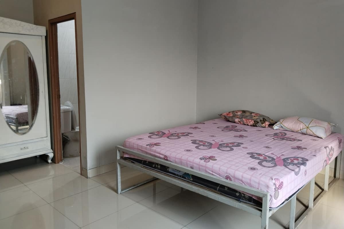 A bedroom with a bed, a dresser, and a mirror.